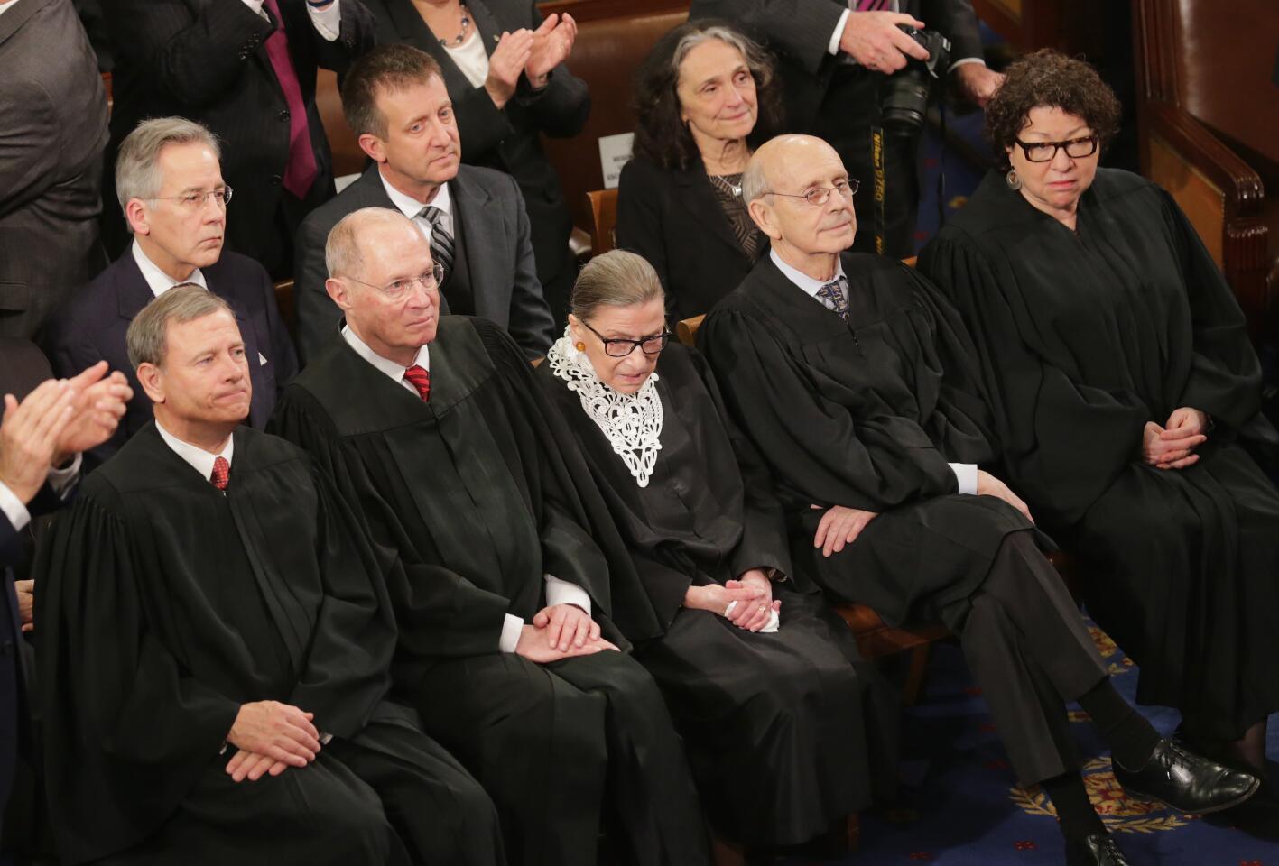 Supreme Court justices wearing black robes sit on a bench in the House chamber during the State of the Union