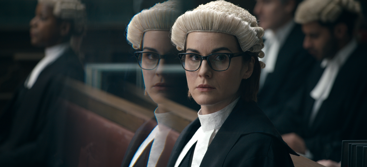 A bespectacled woman in a barrister's wig