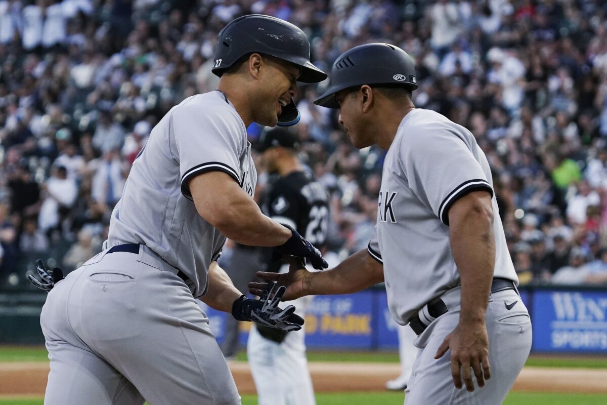 New York Yankees' Giancarlo Stanton, left, celebrates with third base coach Luis Rojas as he runs the bases after hitting a two-run home run against the Chicago White Sox during the first inning of a baseball game in Chicago, Friday, May 13, 2022. (AP Photo/Nam Y. Huh)