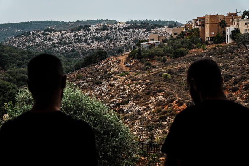 ARAB-AL-ARAMSHE, ISRAEL -- OCTOBER 11, 2023: Local residents take in a view of the neighboring country of Lebanon separated by a border fence and a hill, as seen from the Israeli town of Arab-al-Aramshe, Israel, Wednesday, Oct. 11, 2023. The communities on IsraelOs norther border gird themselves for war amid rising tensions with Iran-backed groups, even as IsraelOs military prepares for a wide scale incursion into Gaza in the countryOs south. (MARCUS YAM / LOS ANGELES TIMES)