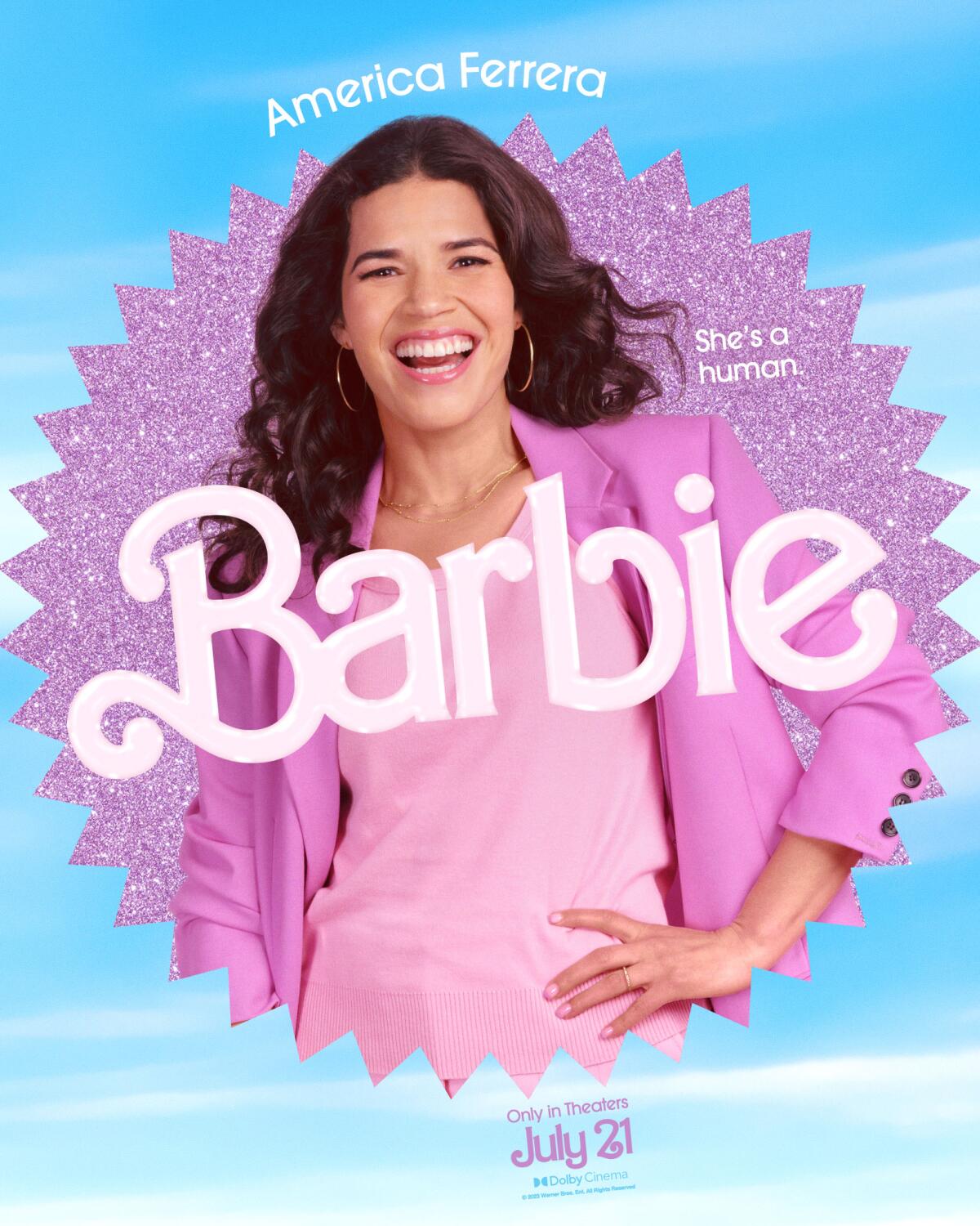 America Ferrera, wearing a pink shirt and blazer, smiles and places her hand on her hip in a movie poster for "Barbie."
