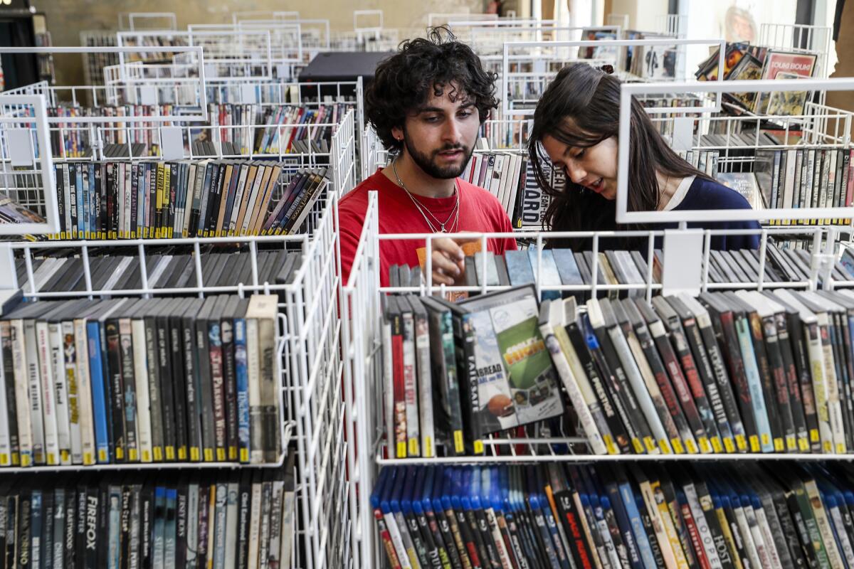 A man and woman look through racks of DVDs