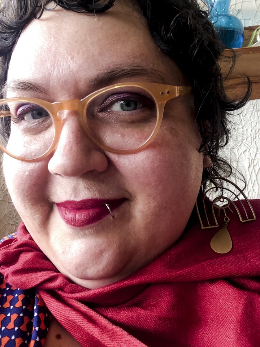 Closeup of a woman with a red scarf and pierced lip.