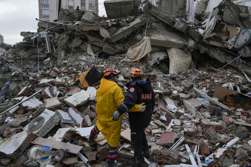 Emergency team members pause for a moment as they search for people in a destroyed building in Adana, Turkey, Monday, Feb. 6, 2023. A powerful quake has knocked down multiple buildings in southeast Turkey and Syria and many casualties are feared. (AP Photo/Khalil Hamra)