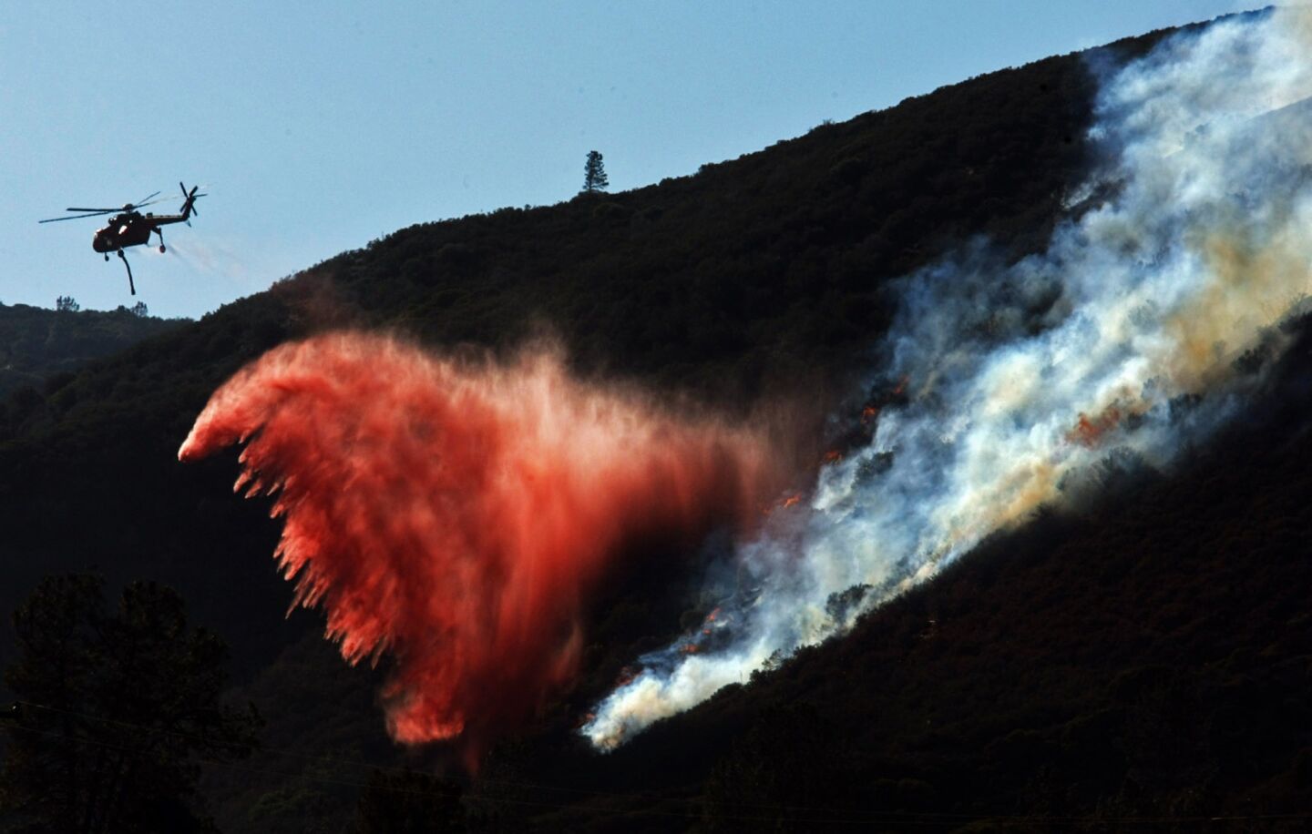 A helicopter drops fire retardant on a ridge near Lake Hughes where the Powerhouse fire continued to burn Monday afternoon.
