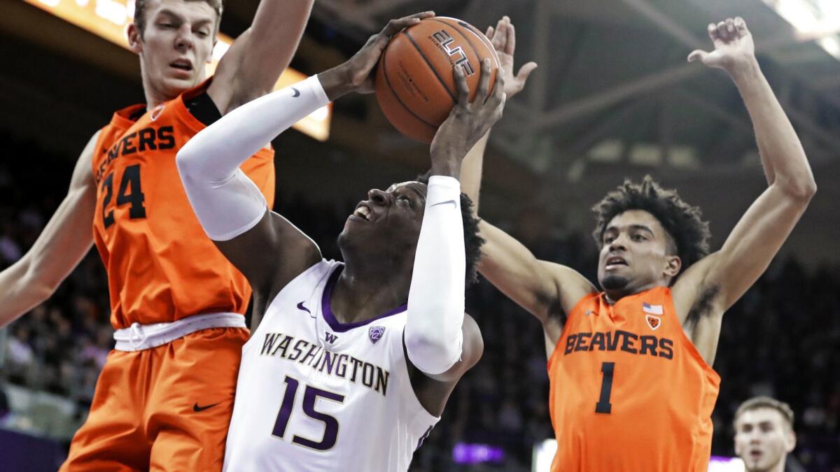 Washington forward Noah Dickerson (15) tries to get a shot off as Oregon State's Kylor Kelley, left, and Stephen Thompson Jr., right, defend during the first half on Wednesday in Seattle.