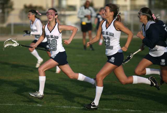 Corona del Mar's Kacie Kline, left, and Cassidy Napolitano run onto the field to celebrate after the Sea Kings won the Battle of the Bay lacrosse match against Newport Harbor on Friday.