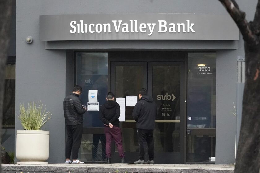 People look at signs posted outside of an entrance to Silicon Valley Bank in Santa Clara, Calif., Friday, March 10, 2023. The Federal Deposit Insurance Corporation is seizing the assets of Silicon Valley Bank, marking the largest bank failure since Washington Mutual during the height of the 2008 financial crisis. The FDIC ordered the closure of Silicon Valley Bank and immediately took position of all deposits at the bank Friday. (AP Photo/Jeff Chiu)