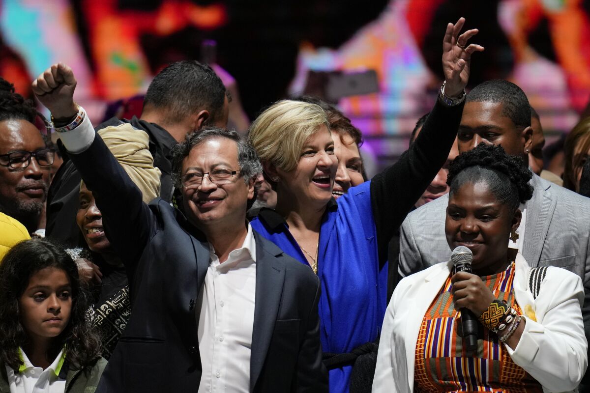 Former rebel Gustavo Petro, left, his wife Veronica Alcocer, back center, and his running mate Francia Marquez, celebrate before supporters after winning a runoff presidential election night in Bogota, Colombia, Sunday, June 19, 2022. (AP Photo/Fernando Vergara)