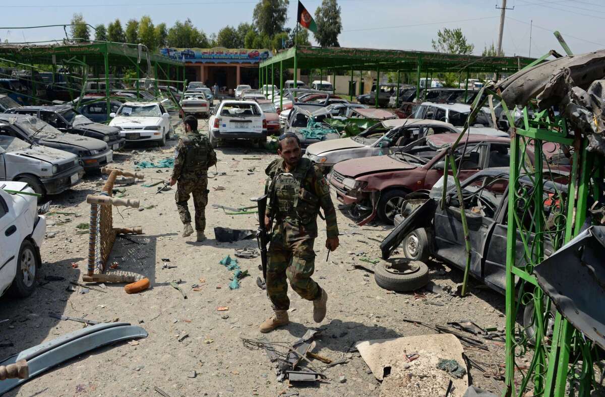 Afghan security personnel walk through the site of a suicide car bomb attack targeting a NATO convoy near the airport in Jalalabad on Friday.