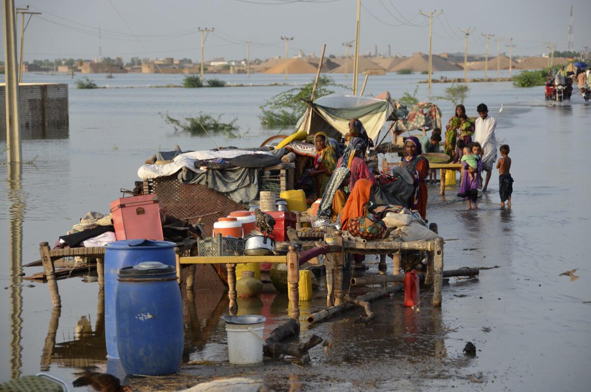 Families sit near their belongings surrounded by floodwaters, in Sohbat Pur city of Jaffarabad.