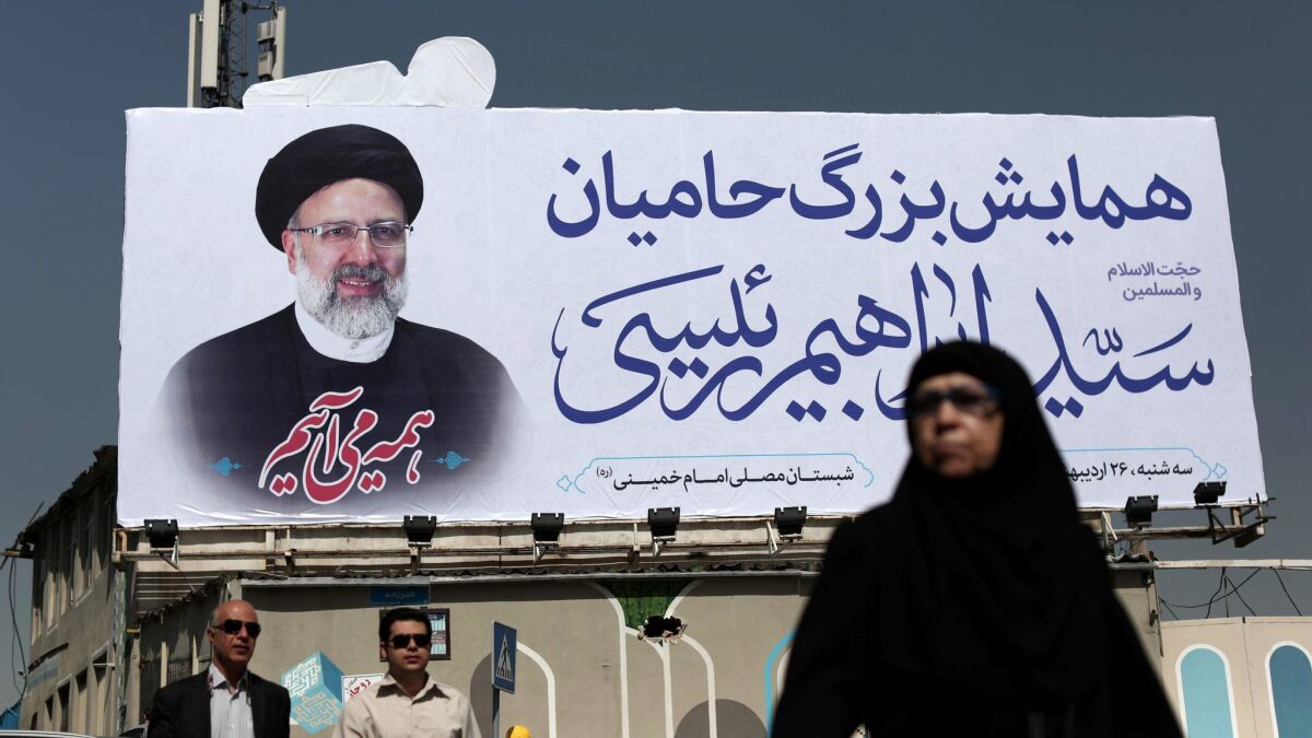 An Iranian woman walks past a portrait of presidential challenger Ebrahim Raisi in Tehran.