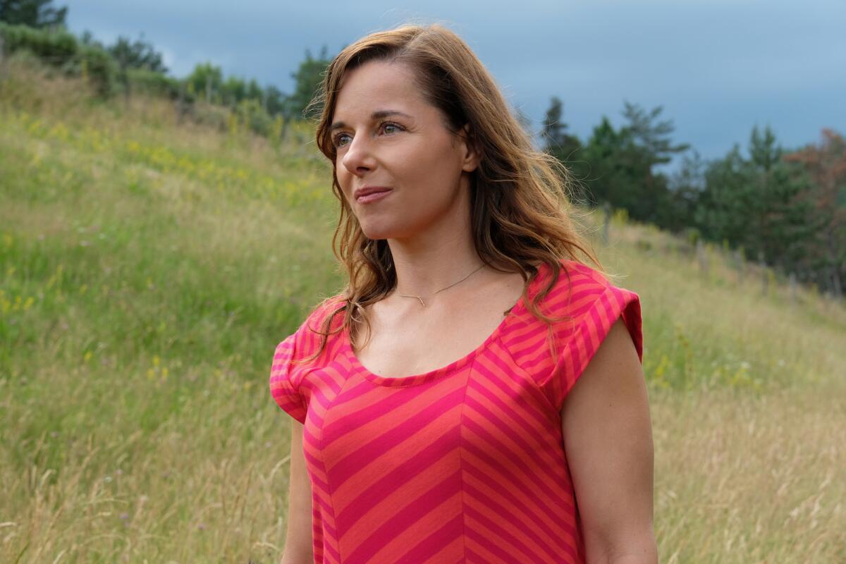 A woman in a red top on a grassy hillside in the movie "My Donkey, My Lover and I."