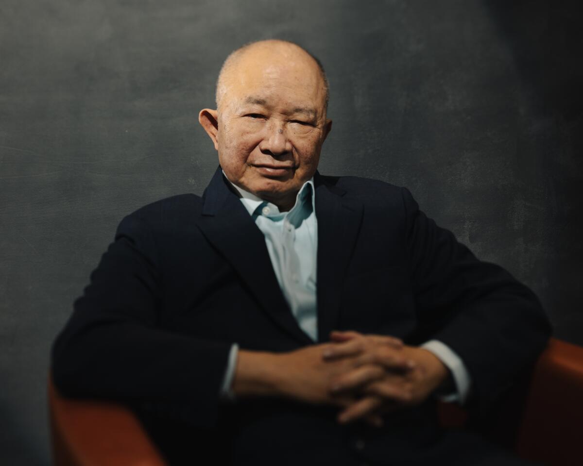 A man in a blue shirt and dark top smiles for the camera.