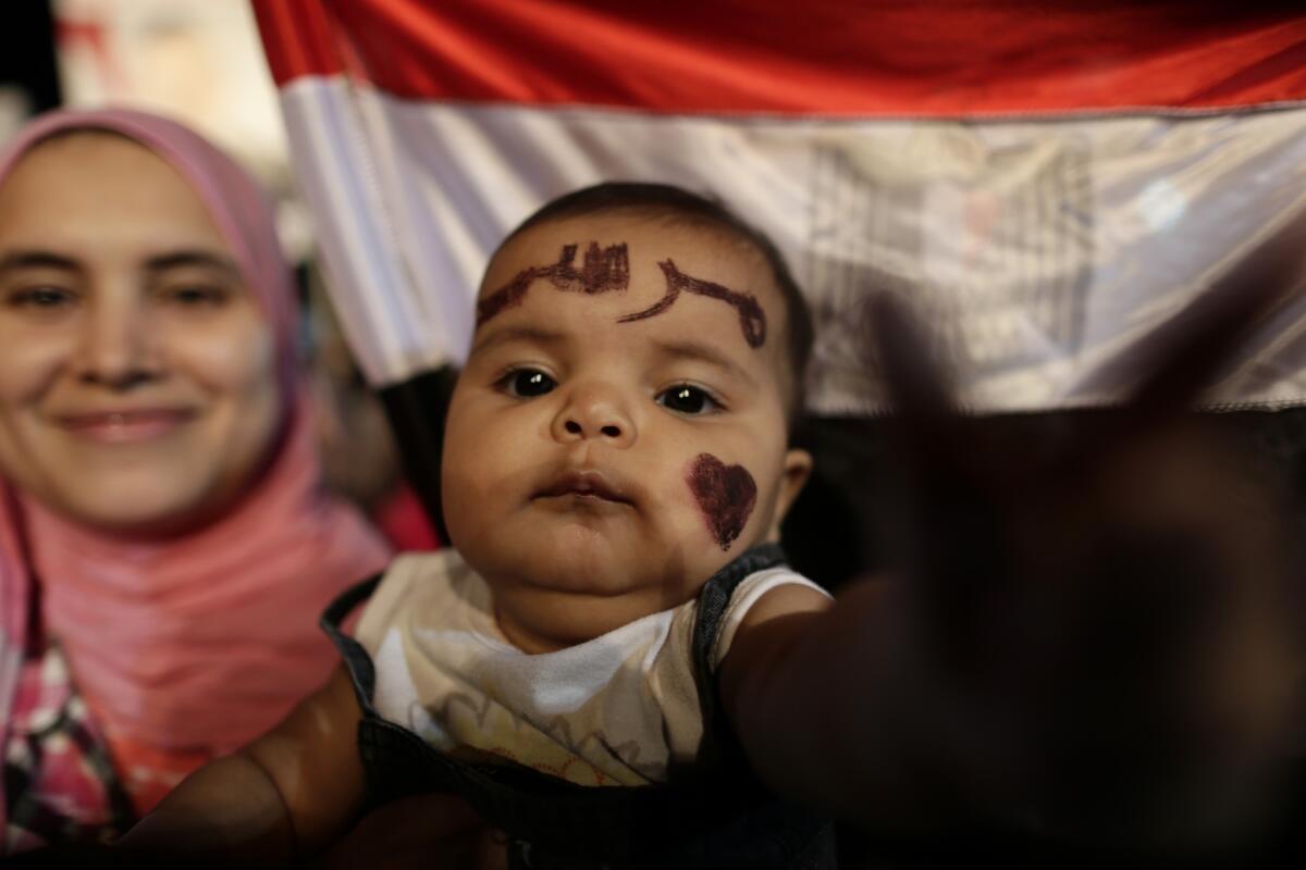 Qurbah, a 6-month-old girl with "Morsi" (in Arabic) painted on her face, attends a demonstration with her mother outside the Rabaa al Adawiya mosque in Cairo.
