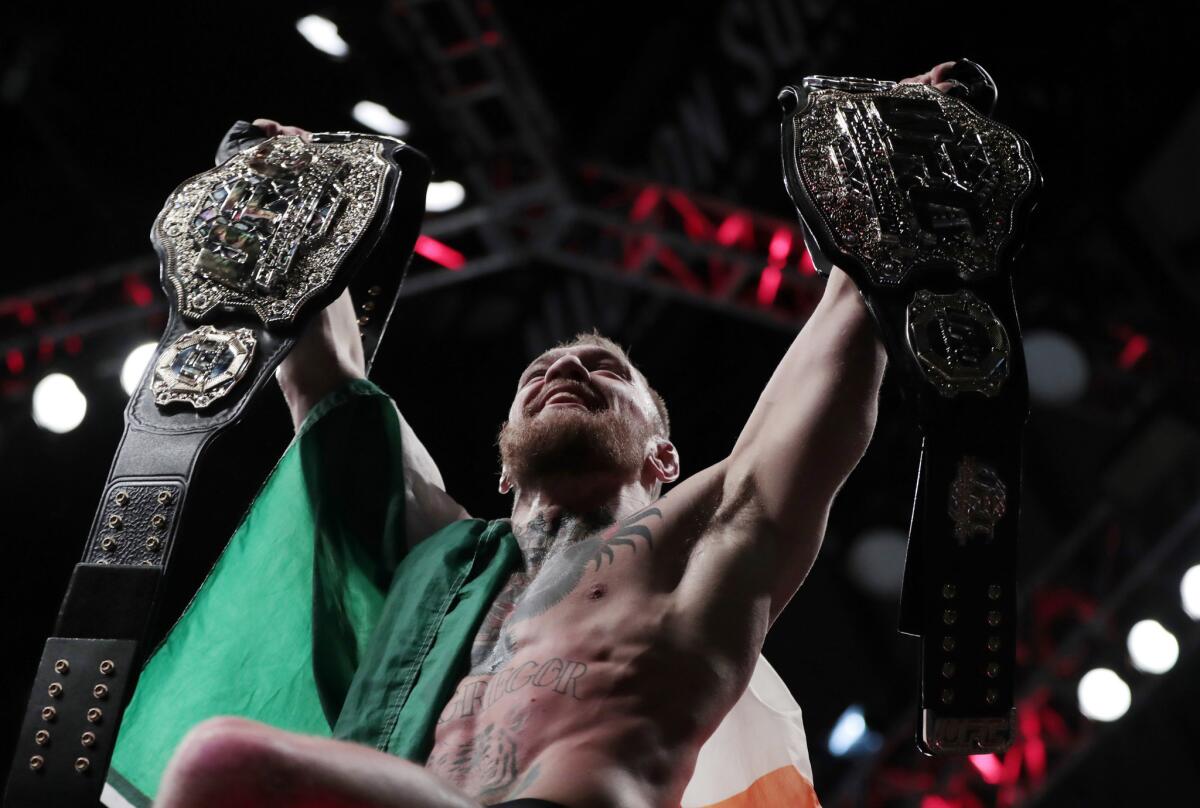 Conor McGregor holds up his title belts after he defeated Eddie Alvarez for the lightweight title at UFC 205.