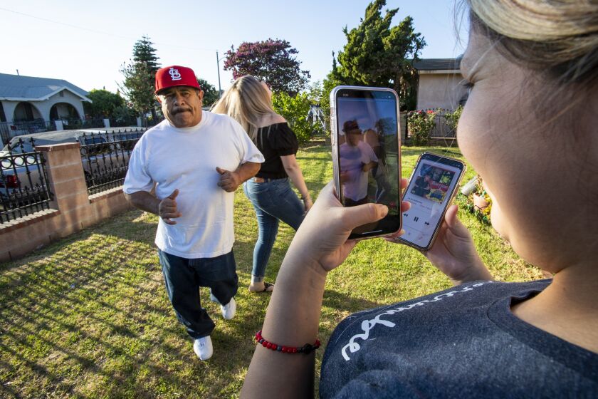 SANTA ANA, CA - JULY 22, 2020: Eveli Paz videotapes her father-in-law Genaro Rangel and sister-in-law Wendy Rangel using the TikTok app while they dance to Latin music for a new fad called Latino Papas on July 22, 2020 in Santa Ana, California. The Rangels are two TikTokkers who've gone viral on the app several times for silly videos.(Gina Ferazzi / Los Angeles Times)