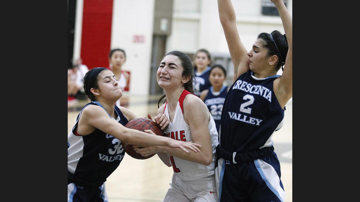 Glendale's Mary Markaryan drives inside to shoot through the defense of Crescenta Valley's Sarah Perez and Georgina Kregorian in a Pacific League girls' basketball game at Glendale High School on Monday, January 8, 2018.
