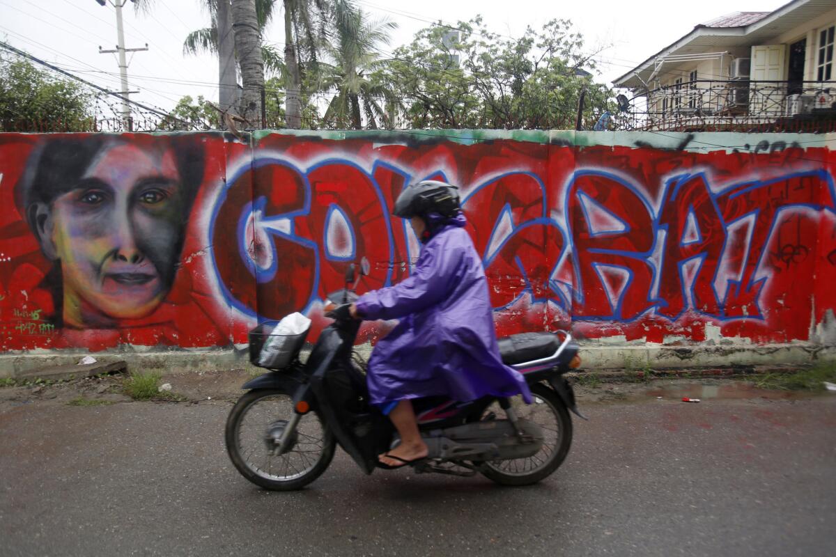 A man rides past graffiti congratulating Myanmar's opposition leader, Aung San Suu Kyi, on her party's expected election win.
