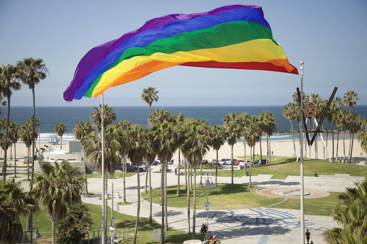 A flying Pride flag near a beach