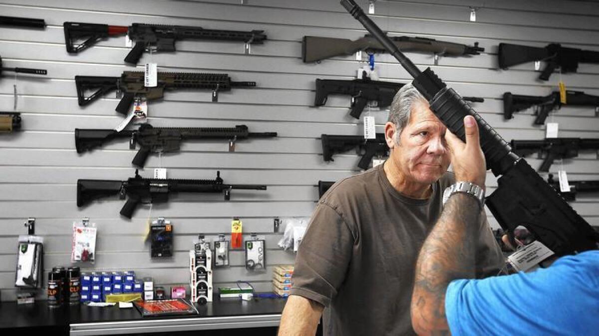 Frank Cobet, de la armería Get Loaded en Grand Terrace, le muestra a un cliente un rifle AR-15 rifle.