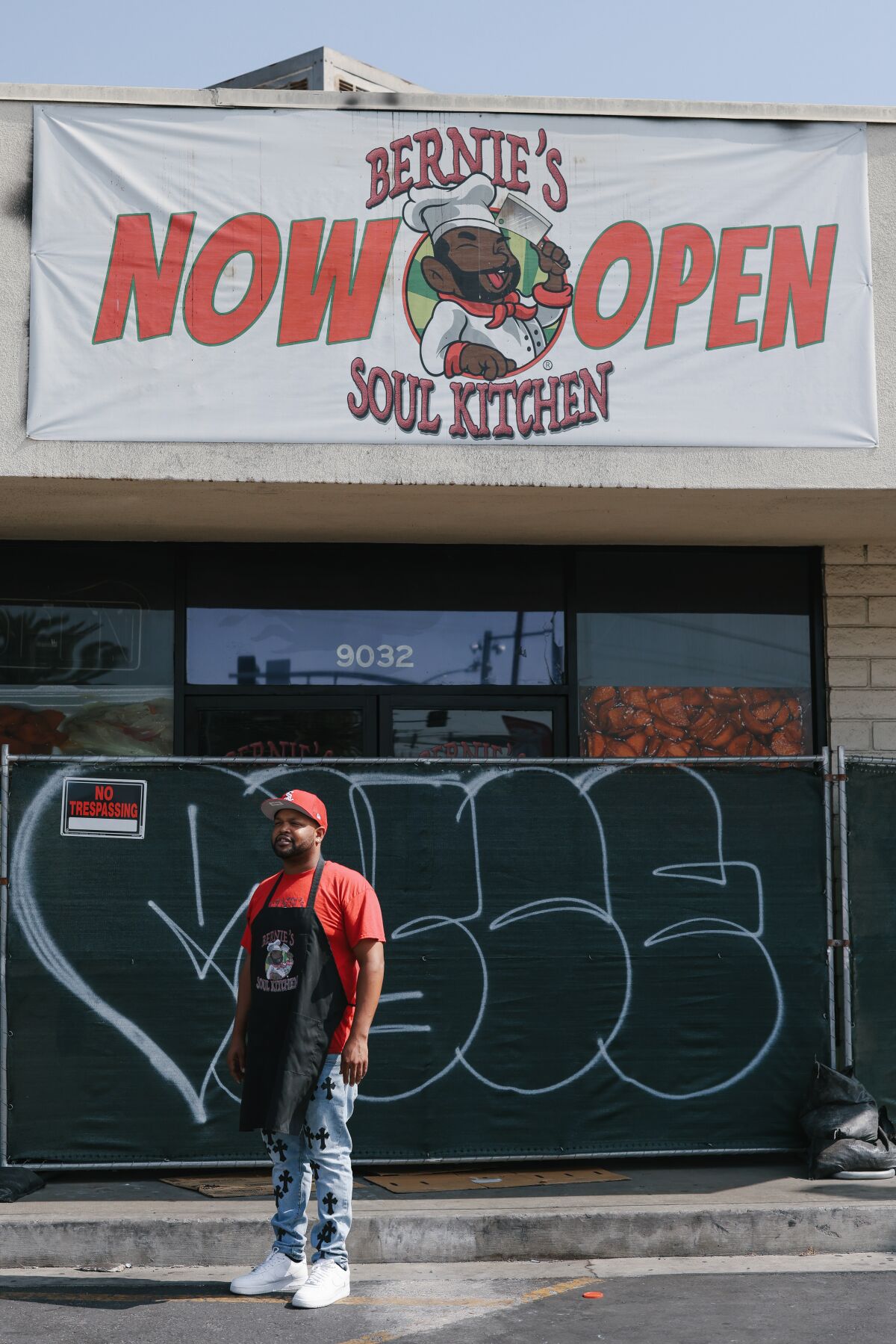 A man stands in front of a restaurant blocked by fencing.