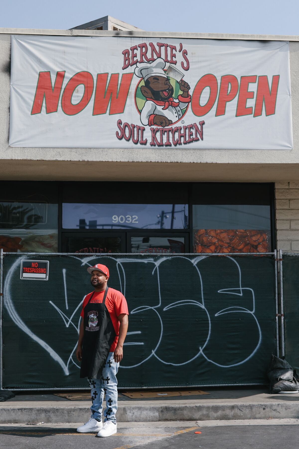 A man stands in front of a restaurant blocked by fencing.