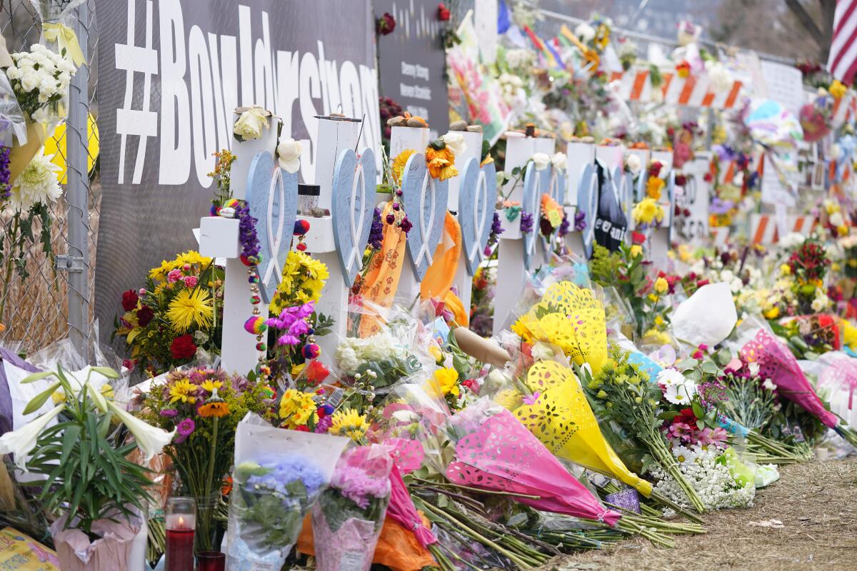 Bouquets are stacked in front of crosses put up for victims outside a King Soopers grocery store in Boulder, Colo.