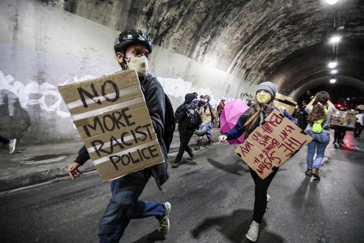 Protesters run from police in the 3rd Street tunnel as they protest the killing of Jacob Blake in Kenosha, Wis.