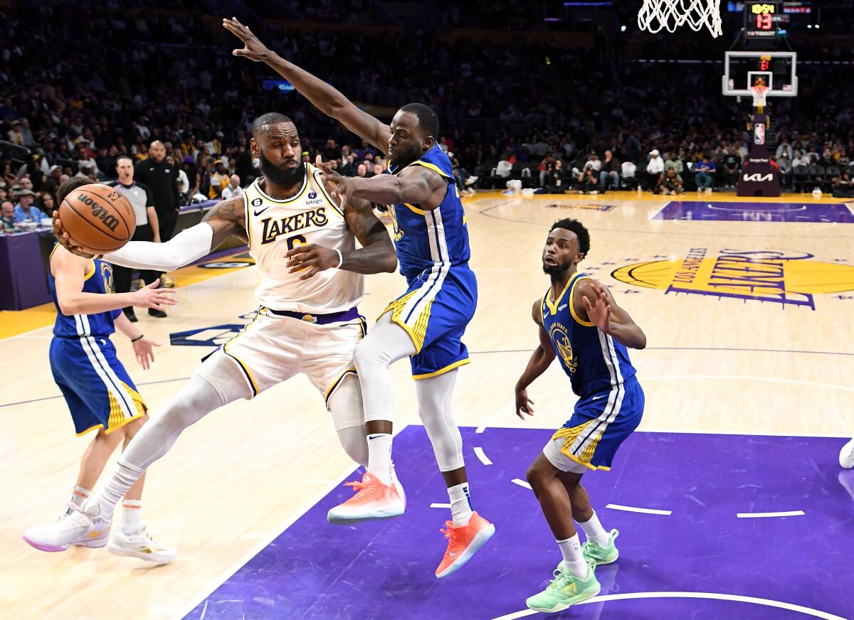 Lakers forward LeBron James leaps along the baseline to throw a pass around Warriors forward Draymond Green.