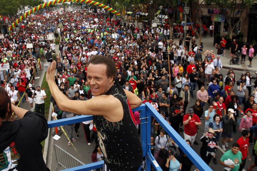 Richard Simmons waving to a group of people from a metal platform in West Hollywood