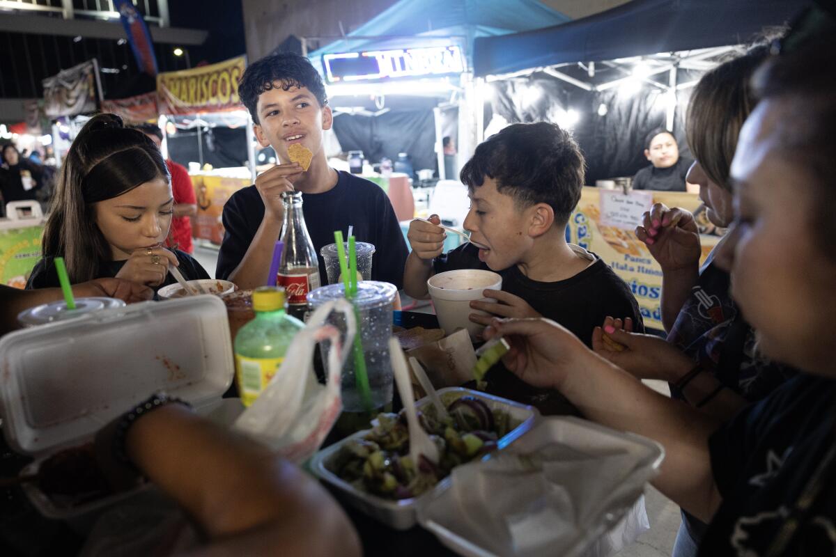 Isaac Morfin smiles as his brother Sebastian and more Morfins eat at El Gato Night Market.