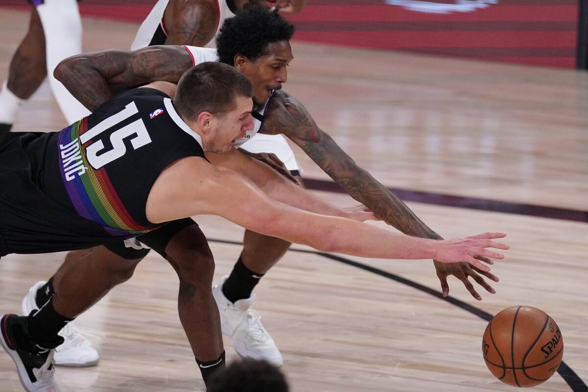 Denver Nuggets' Nikola Jokic and Clippers' Lou Williams battle for a loose ball