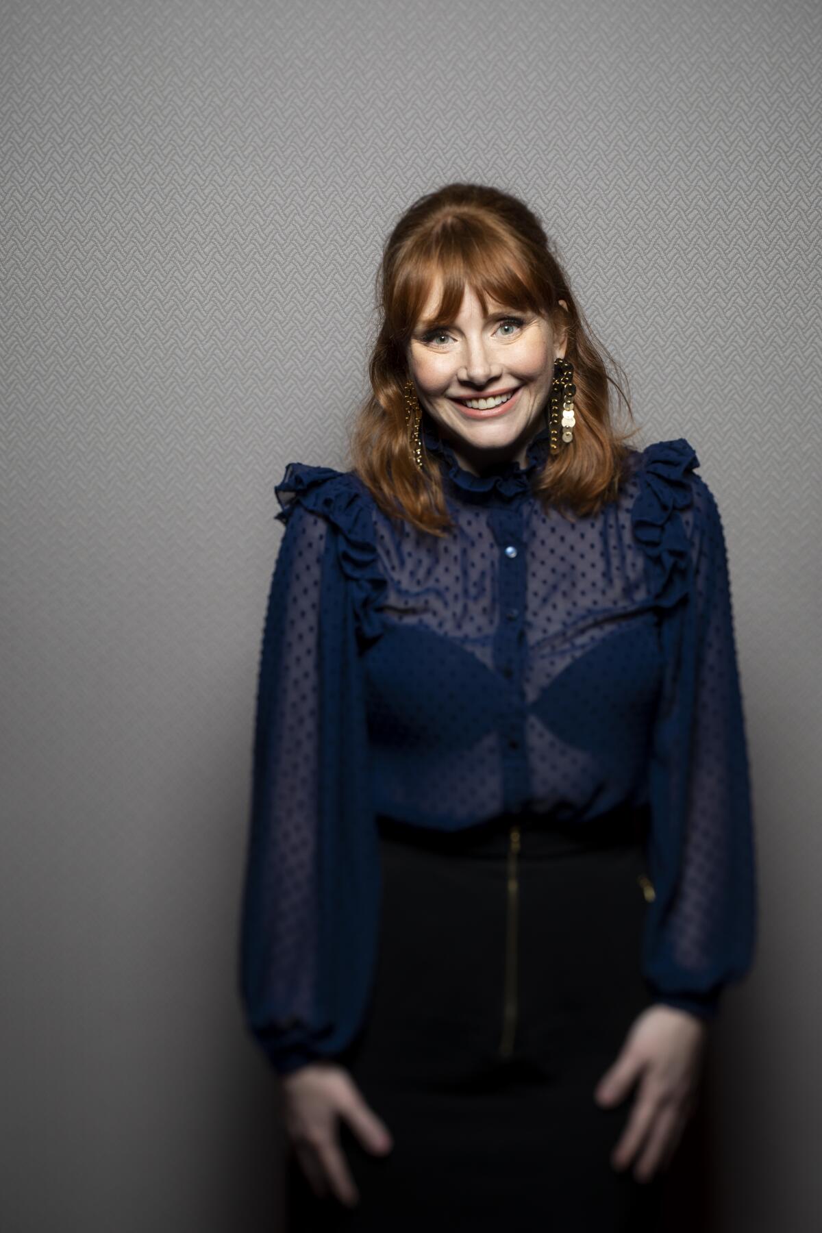 Bryce Dallas Howard, wearing a blue blouse, smiles as she promotes her documentary 'Dads'
