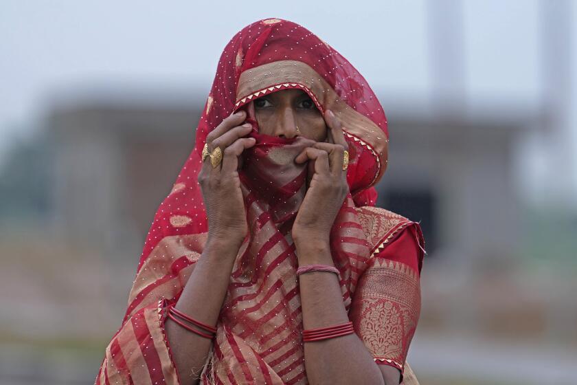 A woman watches members of a forensic team investigate the scene a day after a fatal stampede, in Fulrai village of Hathras district, Uttar Pradesh, India, Wednesday, July 3, 2024. Thousands of people at a religious gathering rushed to leave a makeshift tent, setting off a stampede Tuesday that killed more than hundred people and injured scores. (AP Photo/Rajesh Kumar Singh)