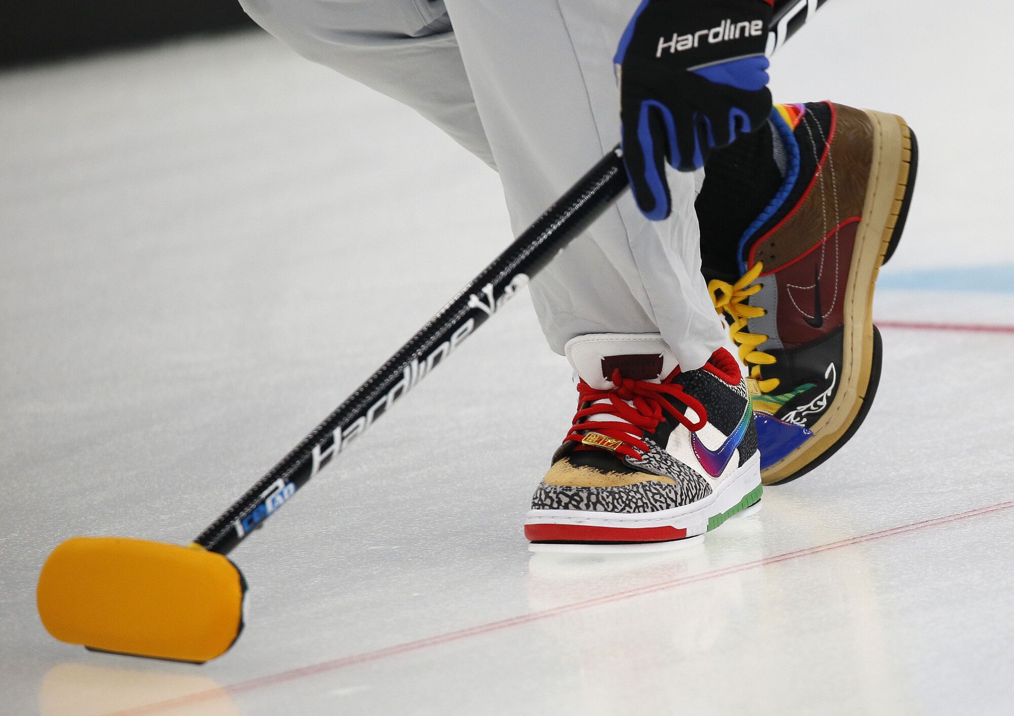 Closeup of two different skate board shoes worn on the ice.