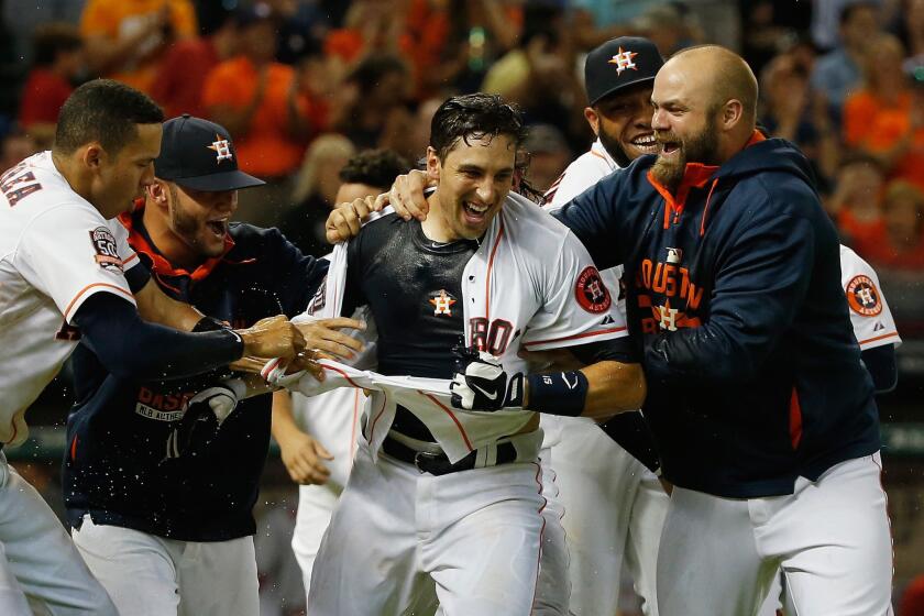 Astros catcher Jason Castro is mobbed and has his jersey ripped off by his teammates after hitting a three-run home run in the ninth inning to win the game against the Angels.