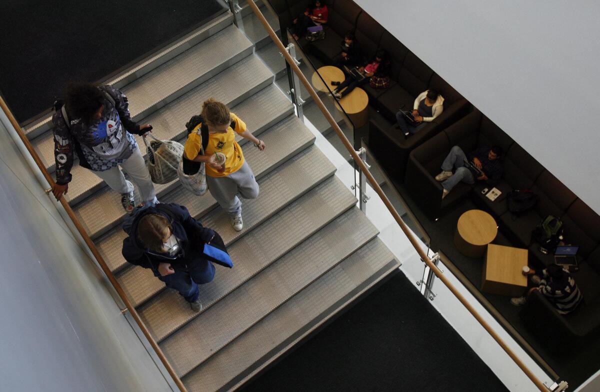 Students walk down a staircase in a library building
