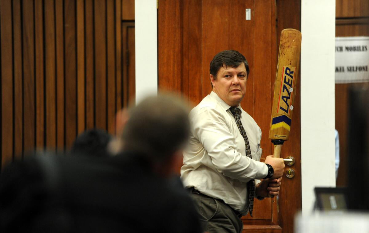 Forensic investigator J.G. Vermeulen, with a cricket bat in hand, on Wednesday demonstrates how the door through which defendant Oscar Pistorius shot and killed his girlfriend could have been broken down with the bat.