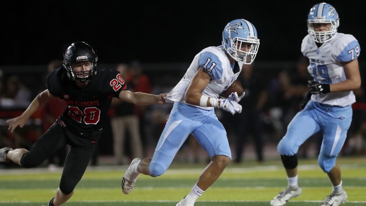 Corona del Mar High wide receiver Bradley Schlom (11) breaks a tackle by San Clemente's Kaleb Glasgow, left, during the first half of a nonleague game on Friday.