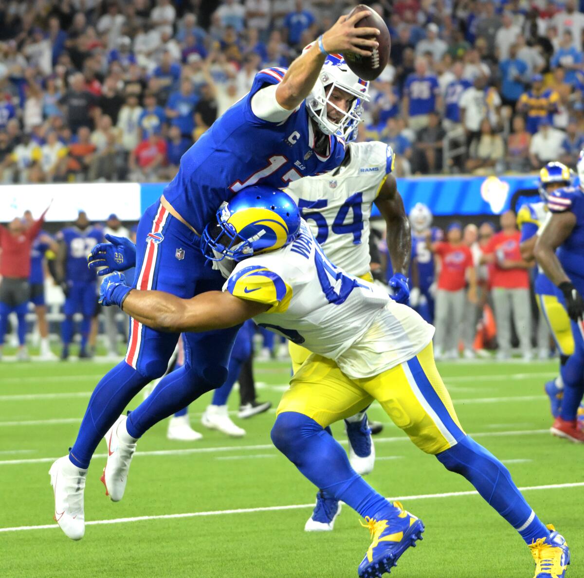 Bills quarterback Josh Allen leaps into the end zone for a touchdown as Rams linebacker Bobby Wagner tries to stop him.