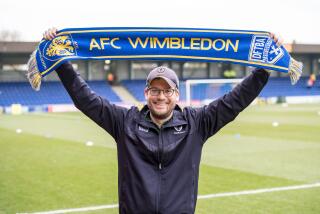 Author John Green holds up an AFC Wimbledon soccer scarf