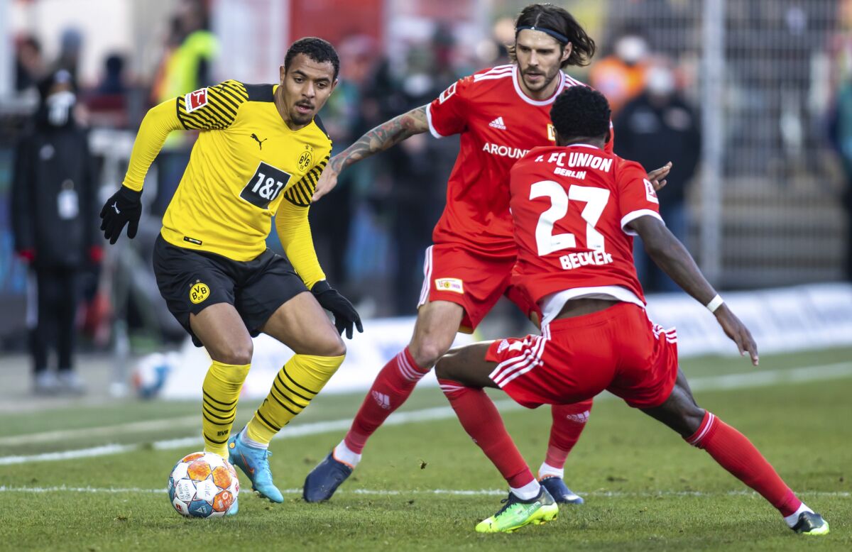 Borussia Dortmund's Donyell Malen, left, fights for the ball with Berlin's Christopher Trimmel and Sheraldo Becker, foregeround, during the German Bundesliga soccer match between Union Berlin and Borussia Dortmund, in Berlin, Sunday, Feb. 13, 2022. (Andreas Gora/dpa via AP)