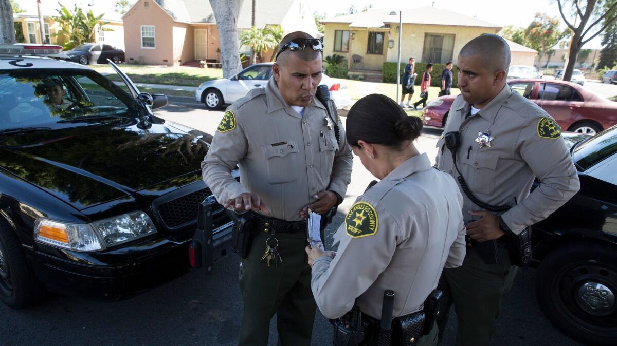 Sheriff's deputy Marino Gonzalez, left, talks with deputies while investigating a disturbance in Maywood.