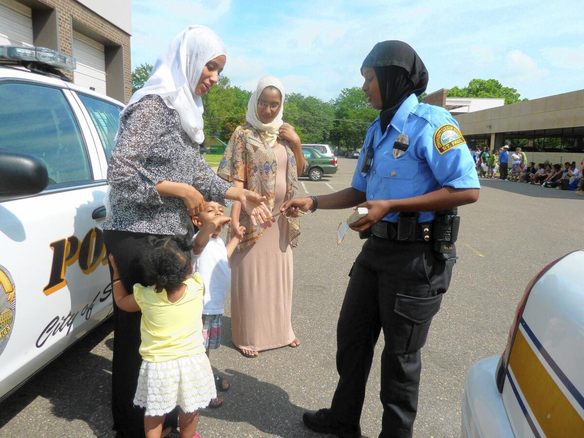 Kadra Mohamed hands out police badge stickers at a community event attended by Somali families. Mohamed is a community liaison officer in St. Paul, Minn., the first Somali woman on the city's police force.