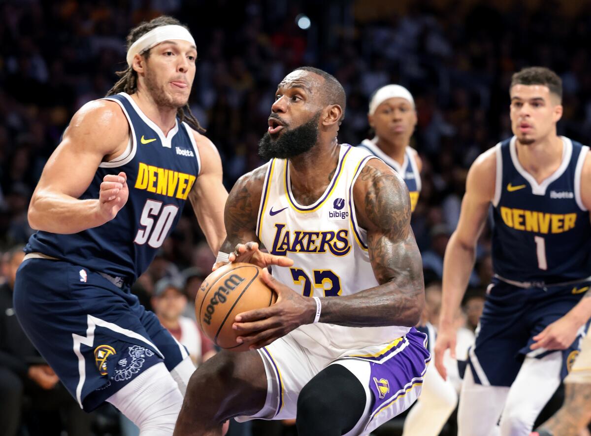 Lakers forward LeBron James, center, drives to the basket against Nuggets forwards Aaron Gordon, left, and Michael Porter Jr.