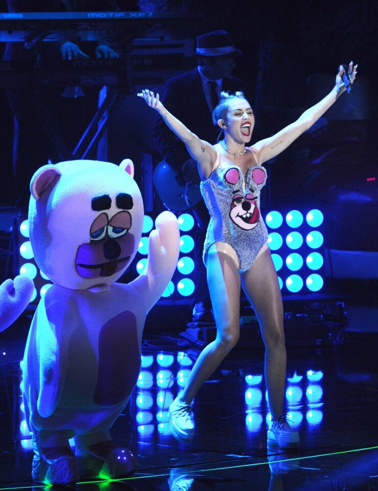 Miley Cyrus dances with giant teddy bears.