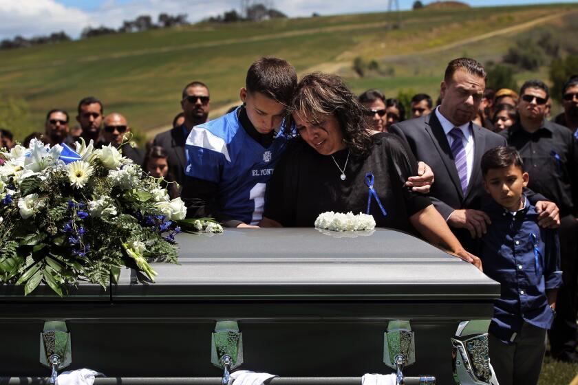 Roman Castro, 16, hugs his mother, Veronica Soriano, as they lean over the casket of Adrien Castro. Castro, 19, was an El Monte High School student who was killed along with nine other people when the bus they were riding in collided head-on with a big rig in Orland, Calif.
