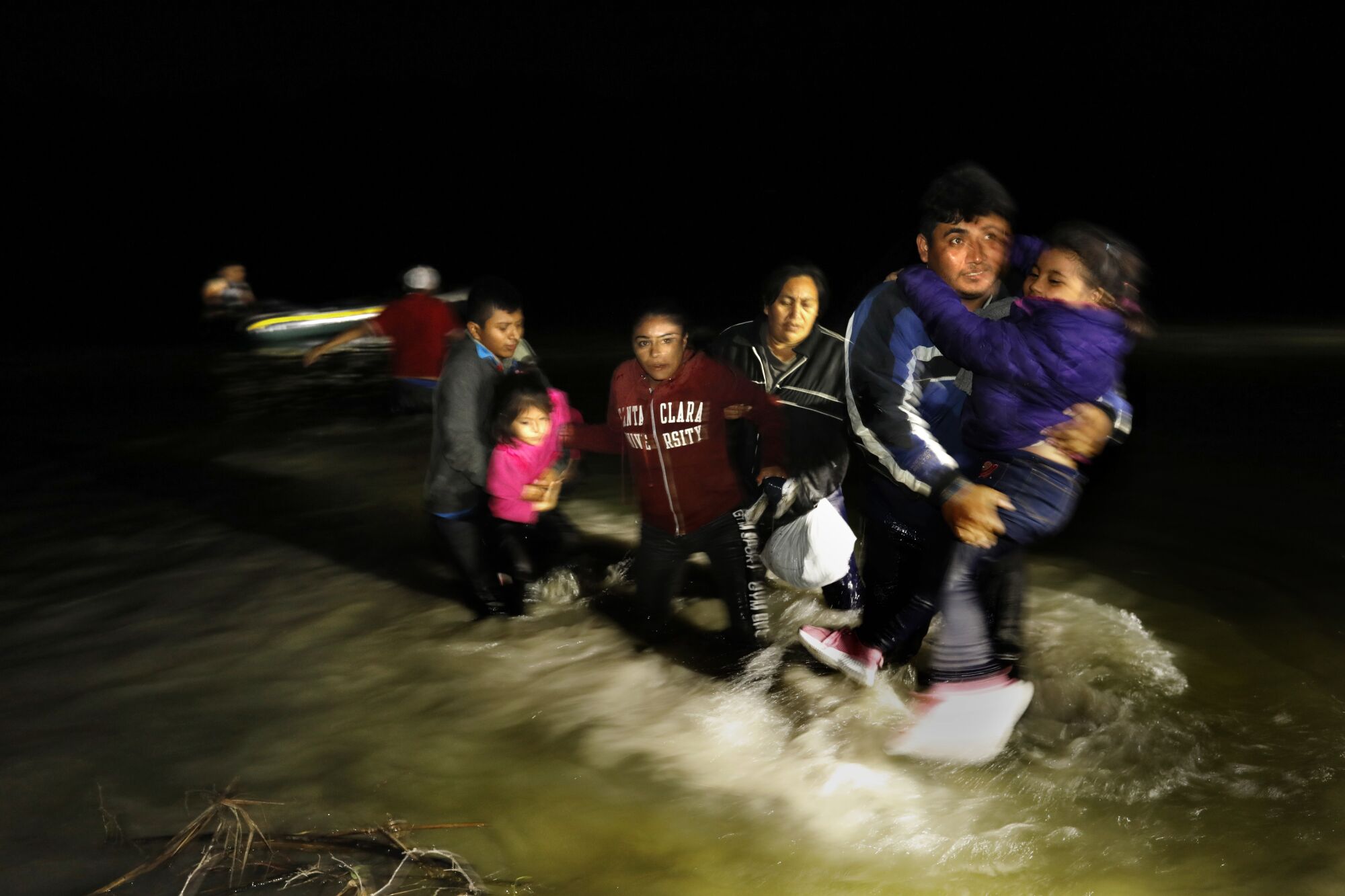A man carries a child as others follow him.