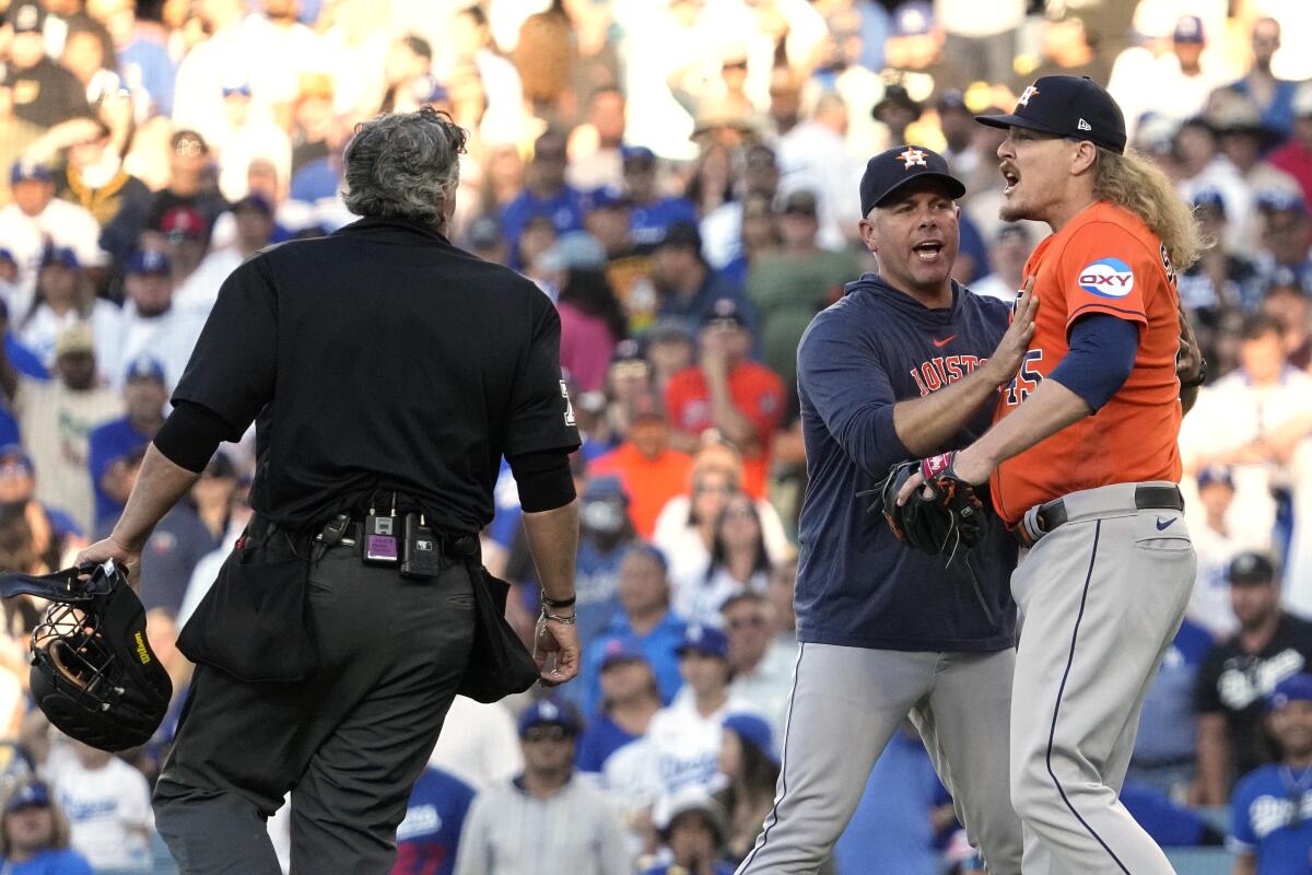 Houston Astros relief pitcher Ryne Stanek, right, is held back by a coach as he yells at second base umpire Junior Valentine while home plate umpire Manny Gonzalez, left, stands by after Stank was called for a balk that allowed a run to score during the eighth inning of a baseball game Saturday, June 24, 2023, in Los Angeles. Stanek was ejected from the game during the argument. (AP Photo/Mark J. Terrill)